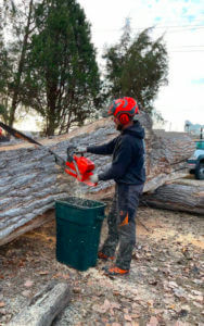 A man using a chainsaw to remove tree debris